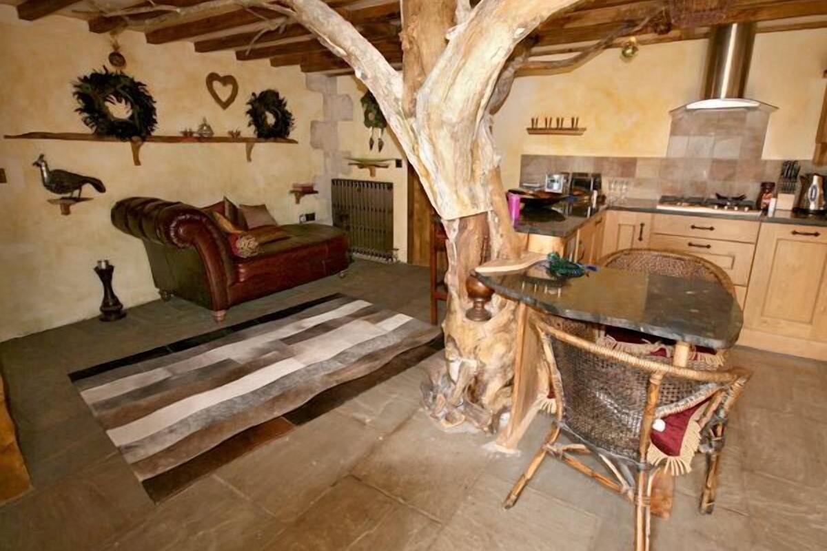 Ein rustikales Interieur mit einem Holztisch, einer Ledersofa und einem großen Baumstamm als Mittelpunkt.