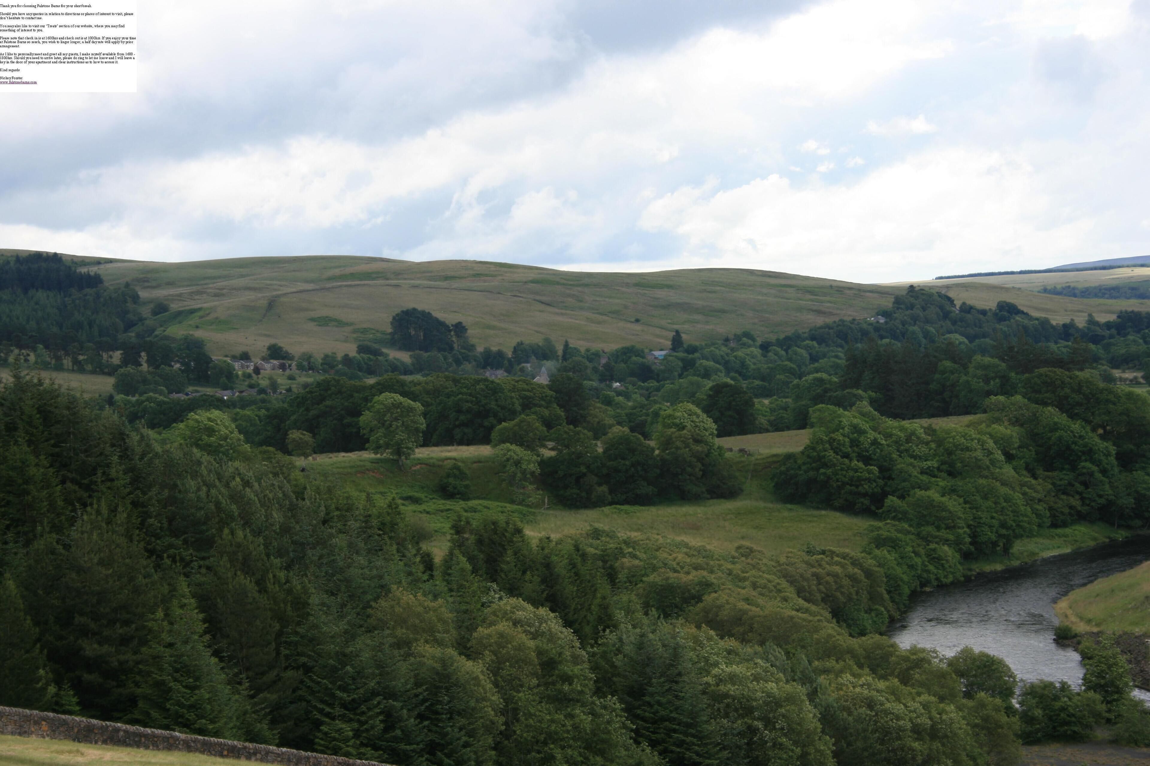 A rural landscape with rolling hills, a river, and scattered trees.