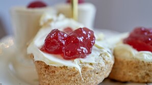 A dessert plate with scones topped with cream and red fruit. - The George (South Molton)