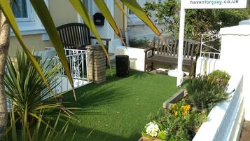 A garden with a lawn, flower beds, and a sign for Haven House B&B.