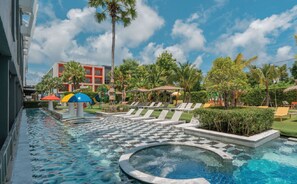 A swimming pool with a hot tub, lounge chairs, palm trees, and a building with red accents. - Sugar Marina Hotel - ART - Karon Beach (Karon)