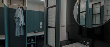 A modern bathroom with a white sink, a large mirror, and a towel rack with robes.