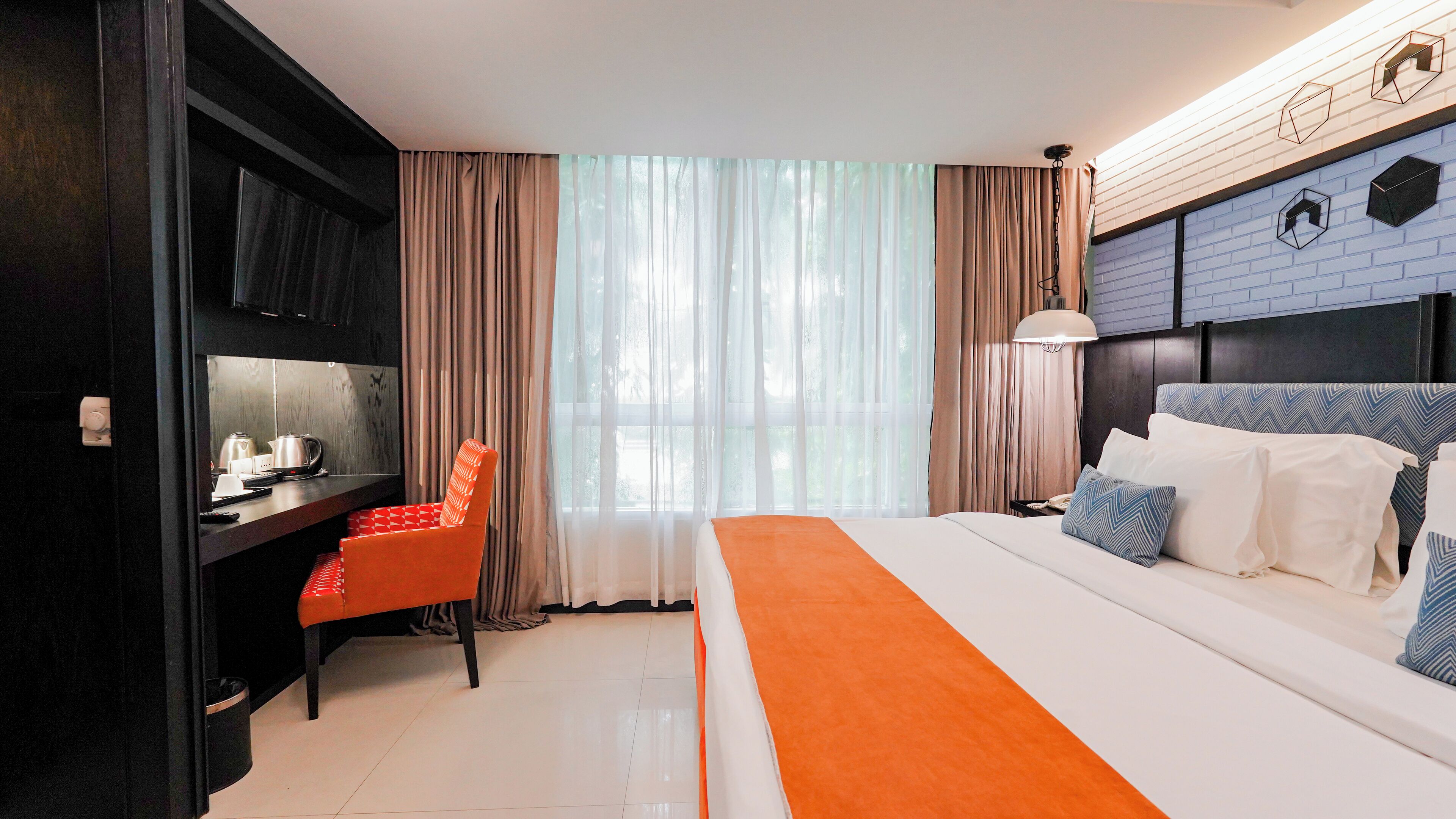 A modern hotel room with a bed, a desk, and a chair.