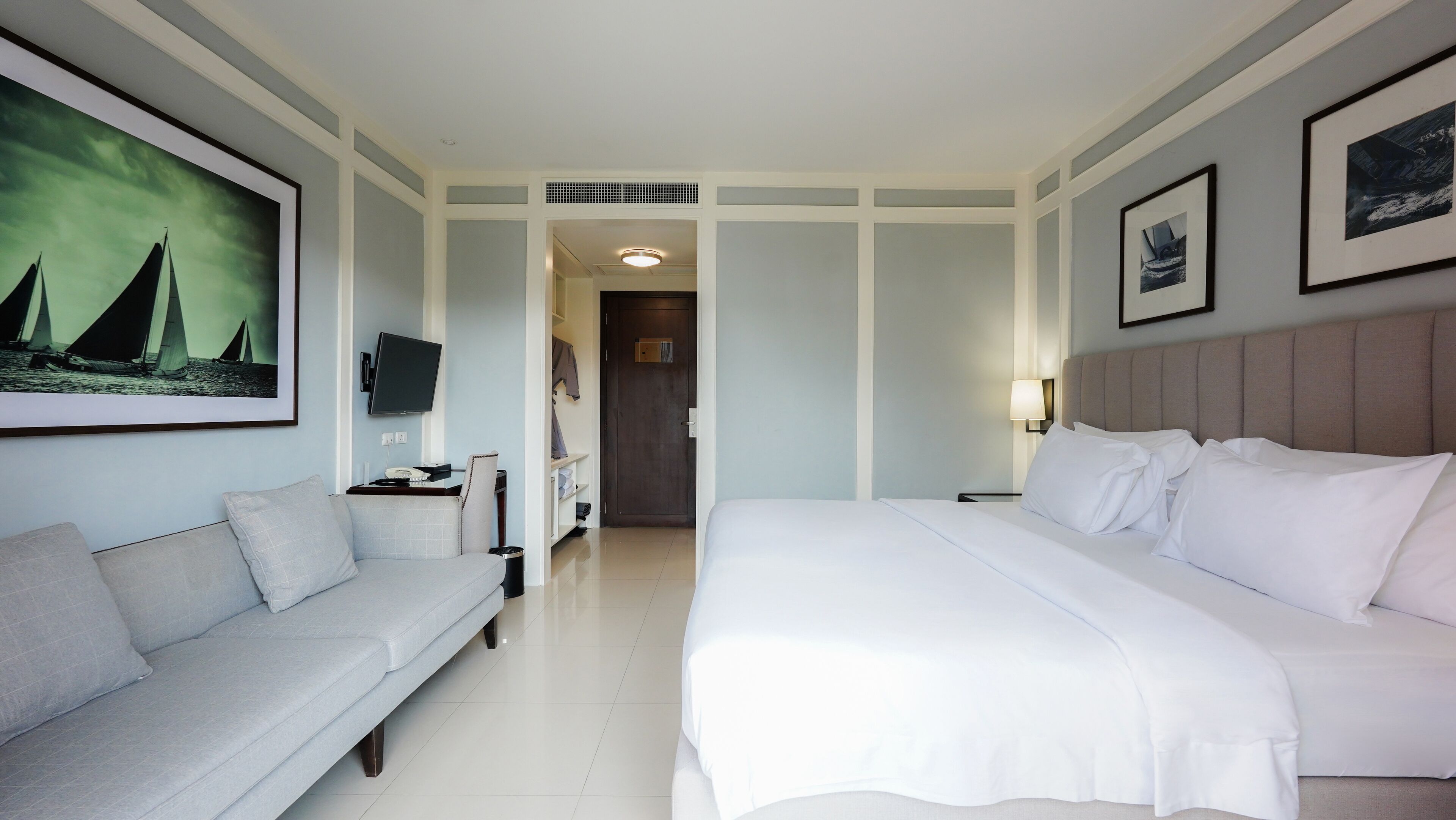 Een hotelkamer met een groot bed, een slaapbank, een flatscreen televisie en kunstwerken aan de muur.