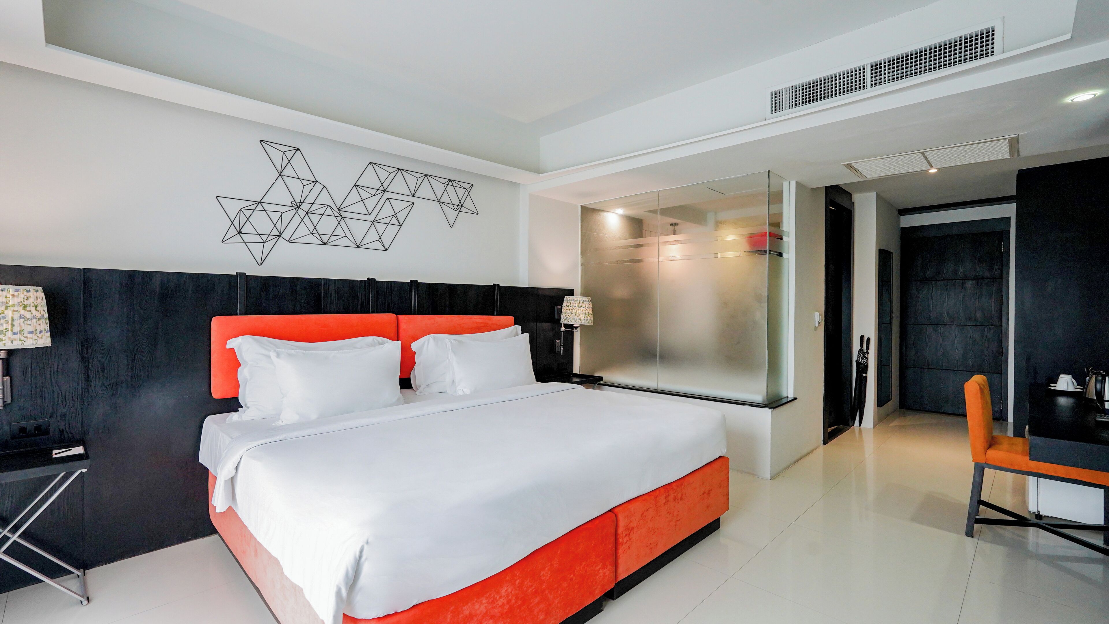 A modern hotel room with a large bed, a desk, and a chair.