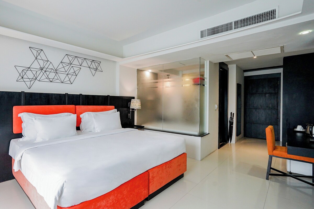 A modern hotel room with a large bed, a desk, and a chair.