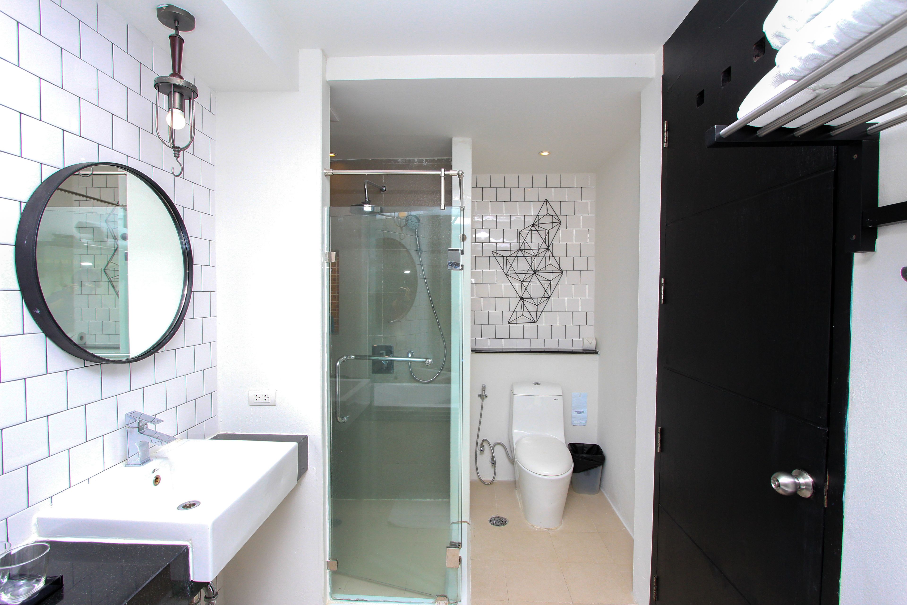 A bathroom with a glass-enclosed shower, a white sink, and a black door.