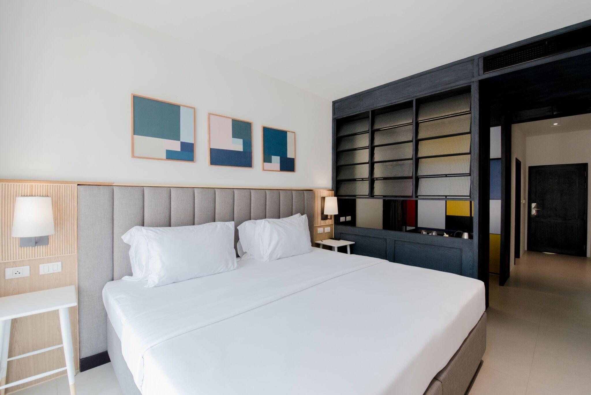 Una habitación de hotel moderna con una cama grande, una mesita de noche y un televisor montado en la pared.