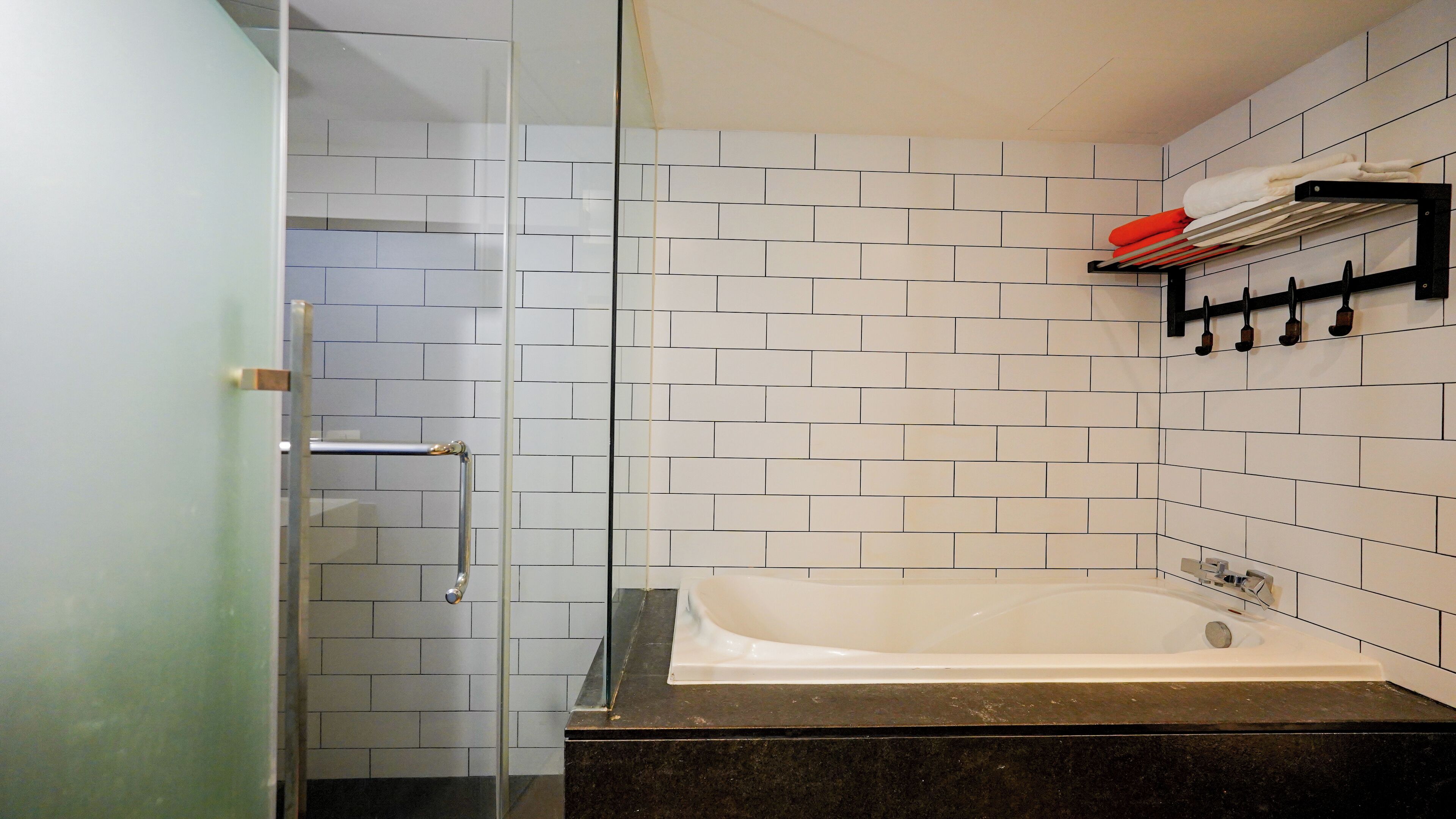 A bathroom with a glass shower enclosure, a white bathtub, and a black countertop.