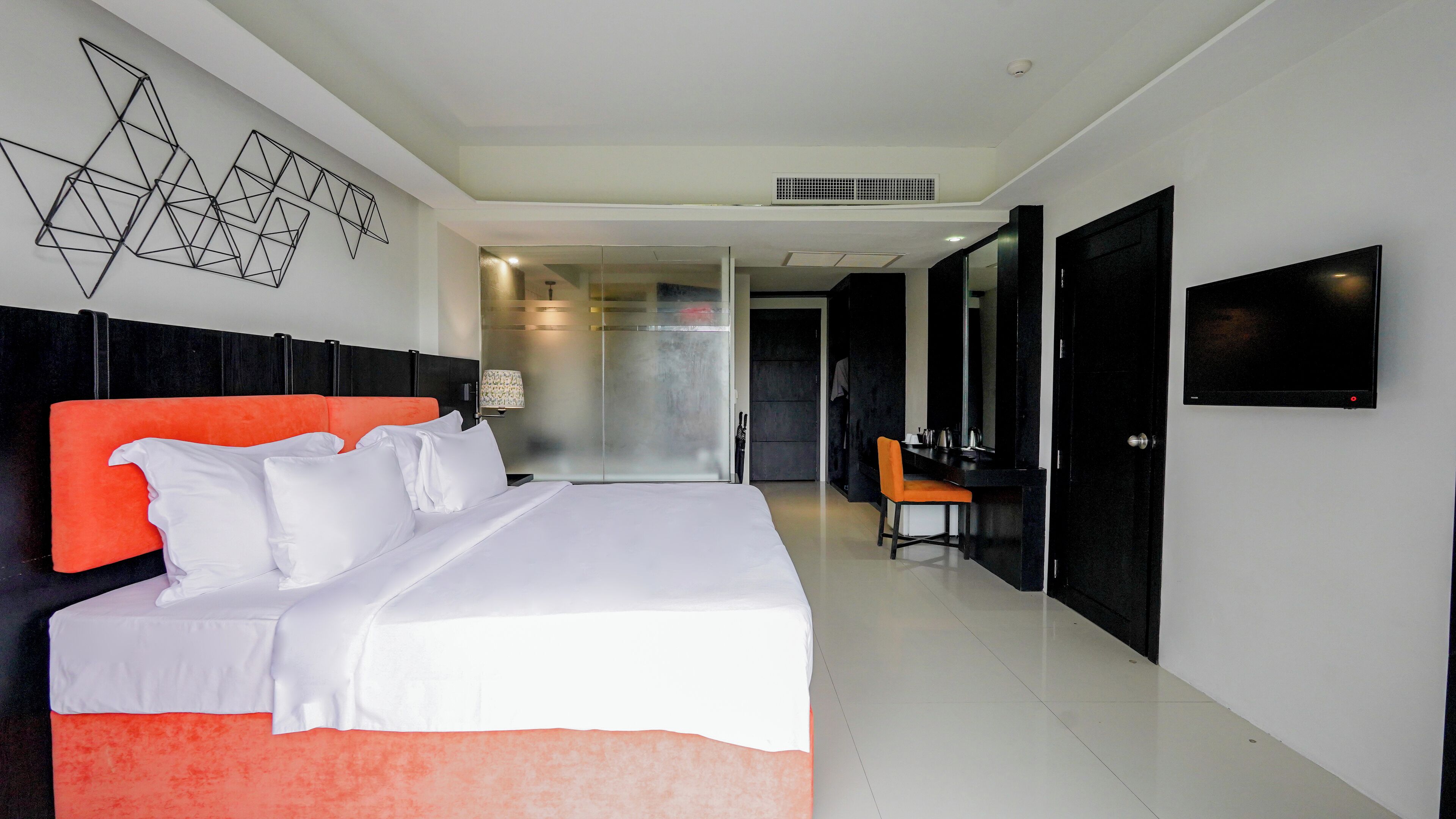 Una habitación de hotel moderna con una cama grande, un escritorio y un televisor.