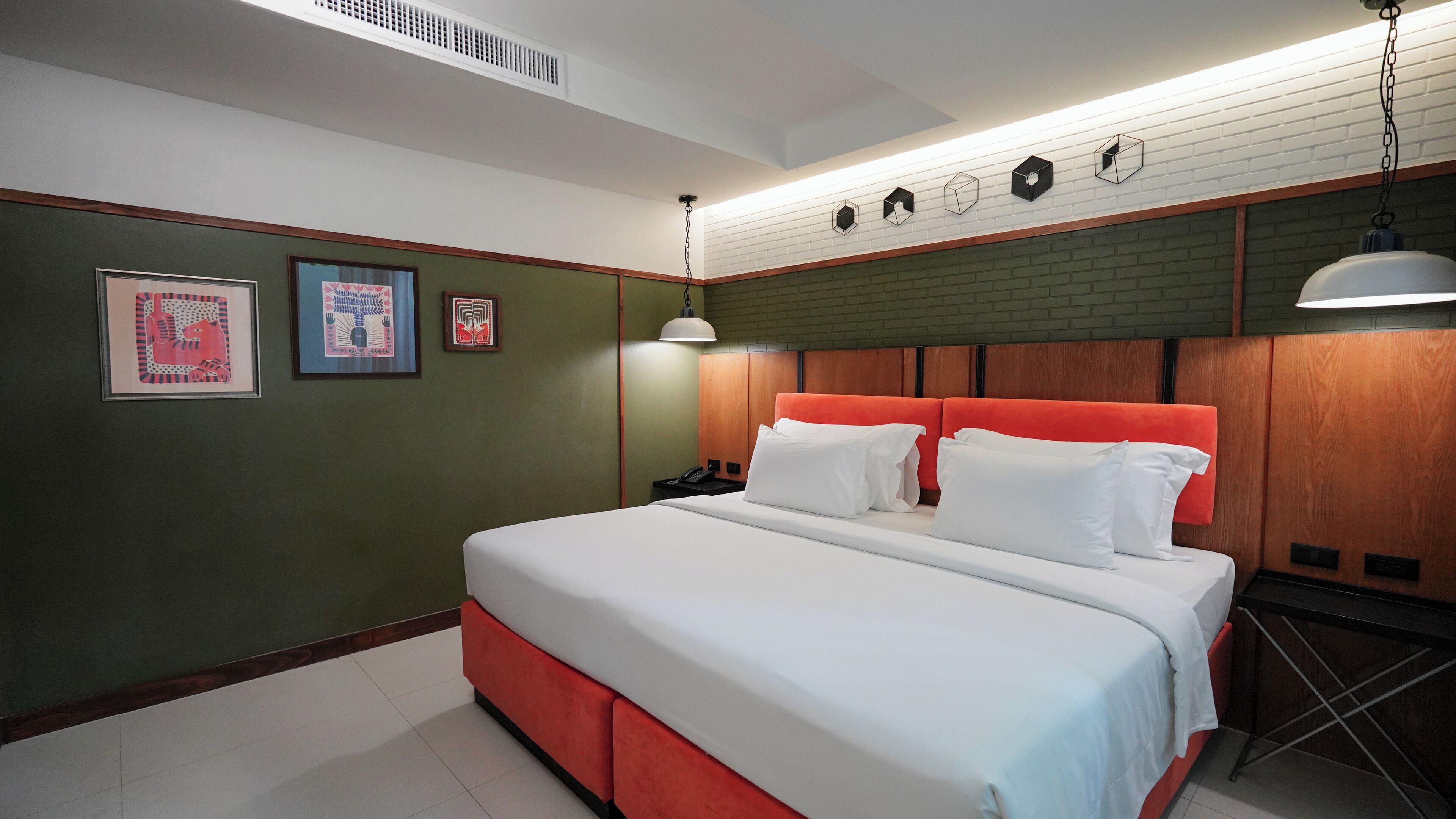 Une chambre d’hôtel moderne avec un grand lit, une tête de lit en bois et un mur décoratif en briques.