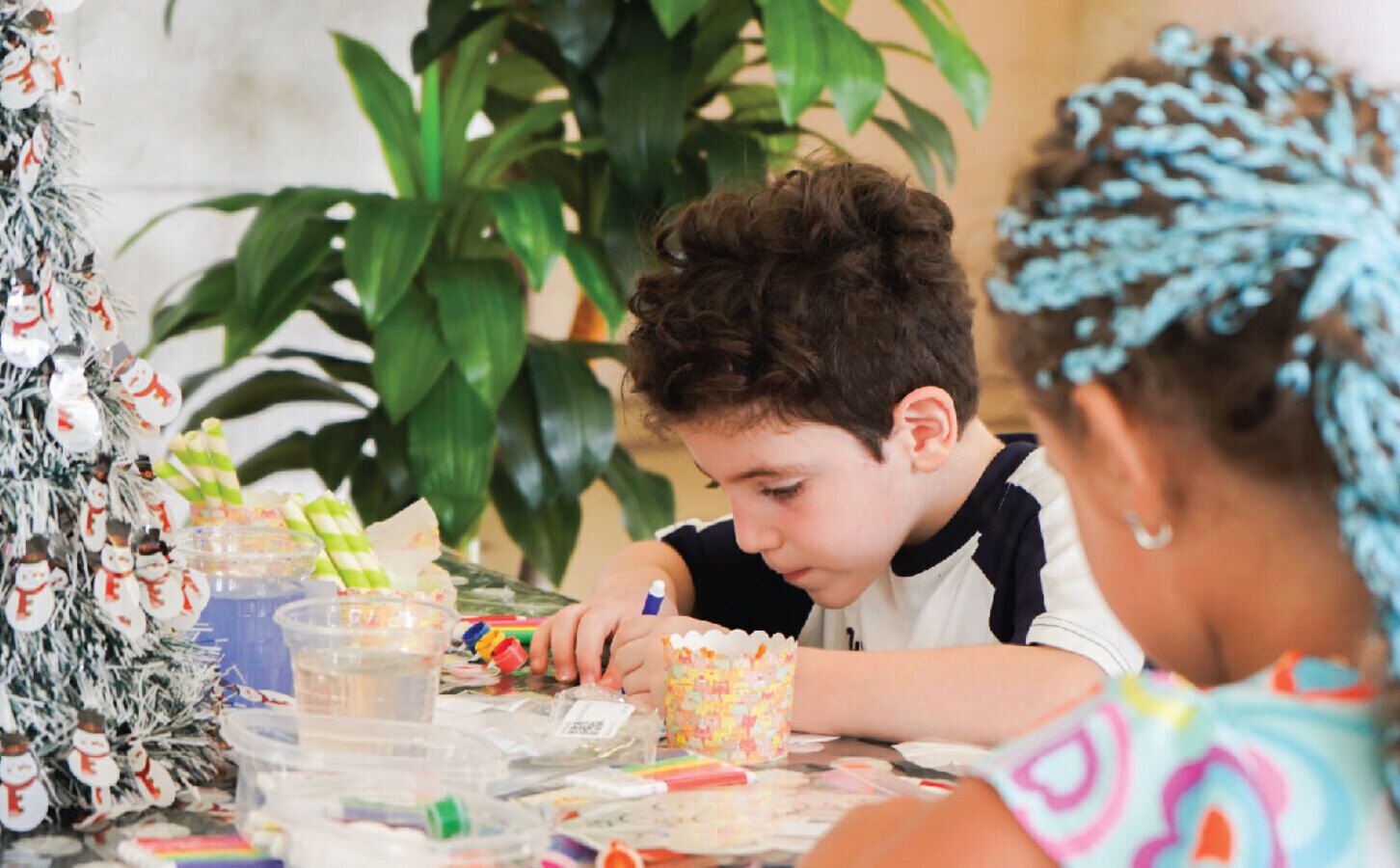 A child engaged in a craft activity at a table with various art supplies.