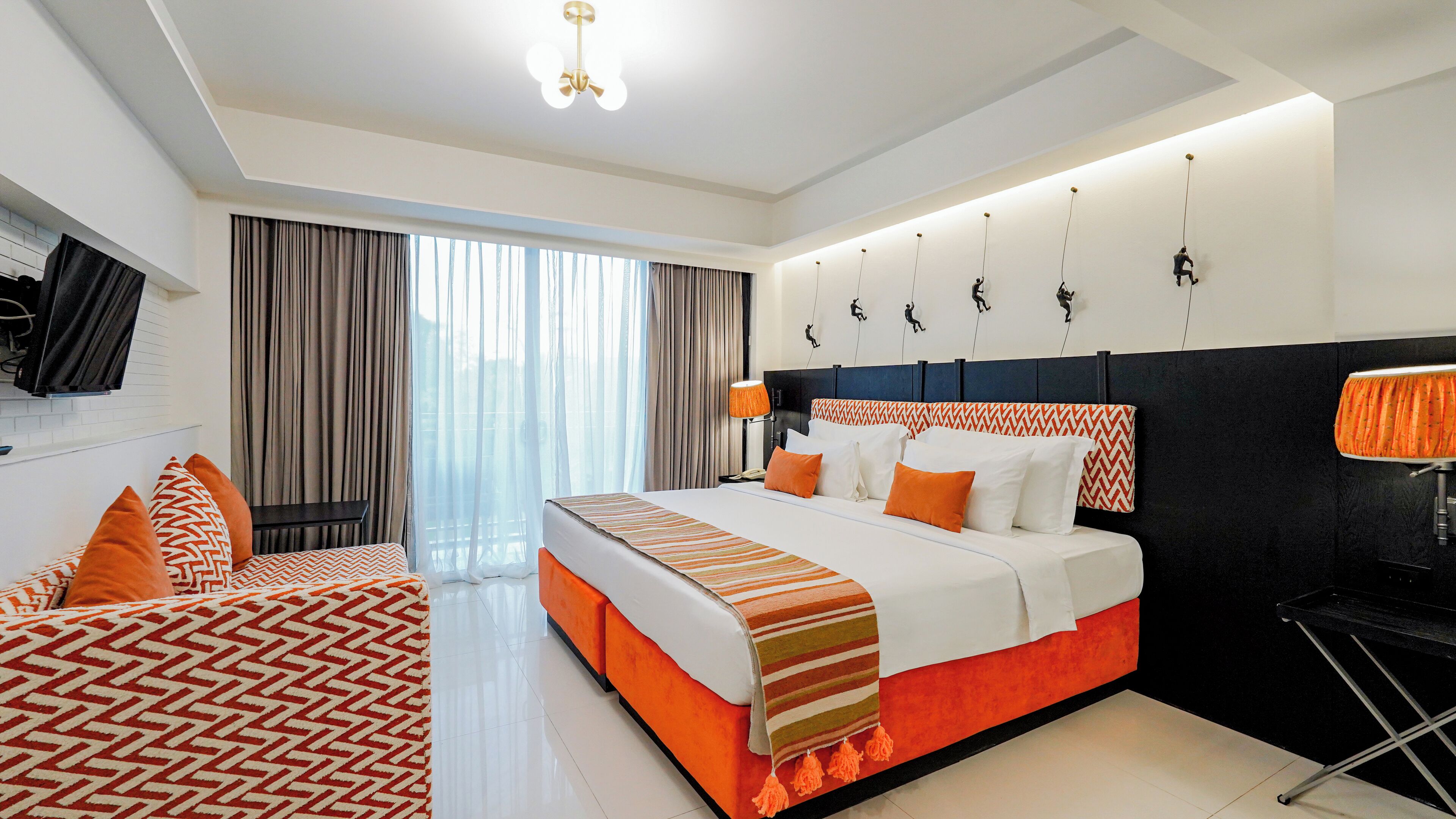 A modern hotel room with a large bed, a smaller bed, a TV, and a desk.