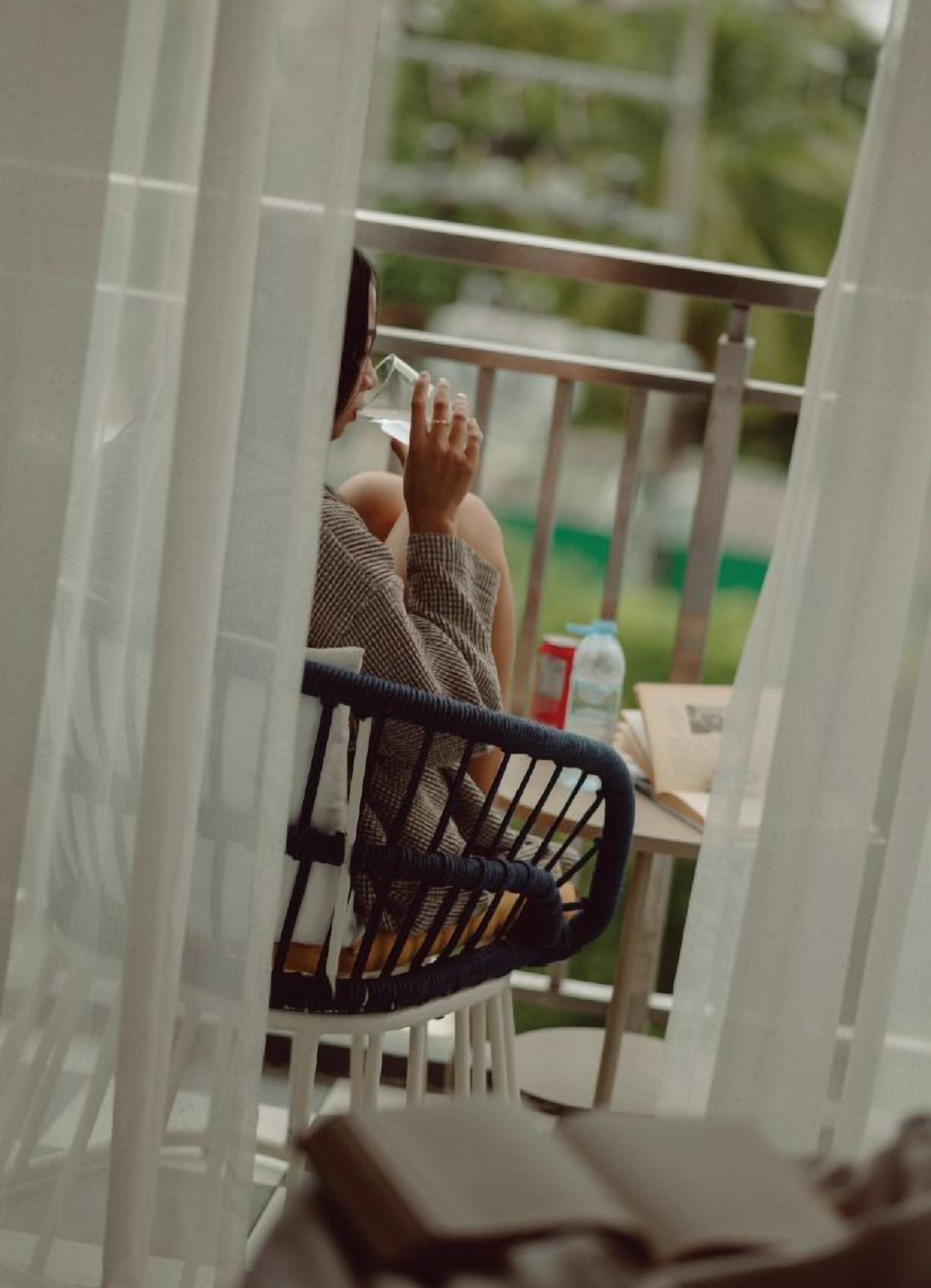 A person sitting on a chair with a white frame, holding a glass.