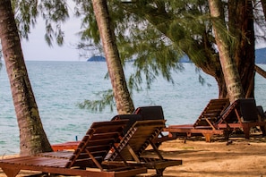 A beach with wooden lounge chairs and a view of the sea. - Anahata Resort Samui (Koh Samui)