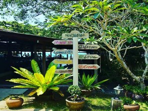 A signpost with multiple directional signs, surrounded by lush greenery and potted plants. - Anahata Resort Samui (Koh Samui)