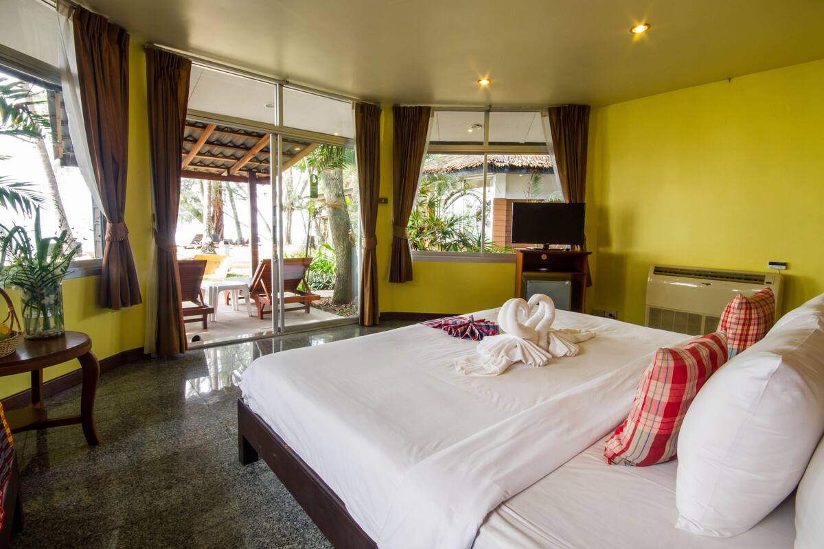 A hotel room with a large bed, a TV, a desk, and a view of the outdoors.