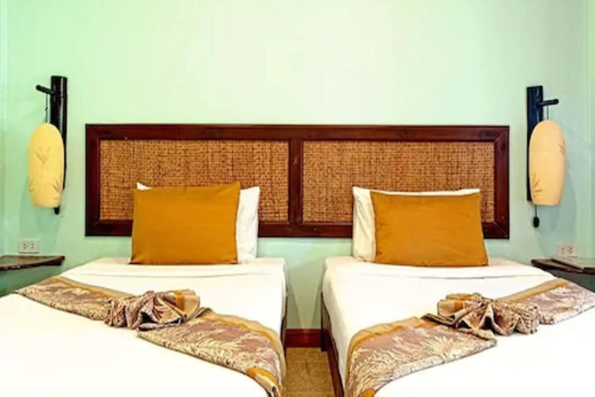 A hotel room with two beds, each with a patterned bedspread and a wooden headboard.