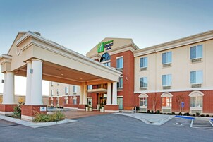 Un hotel Holiday Inn Express con entrada cubierta, estacionamiento para huéspedes y fachada de ladrillo.