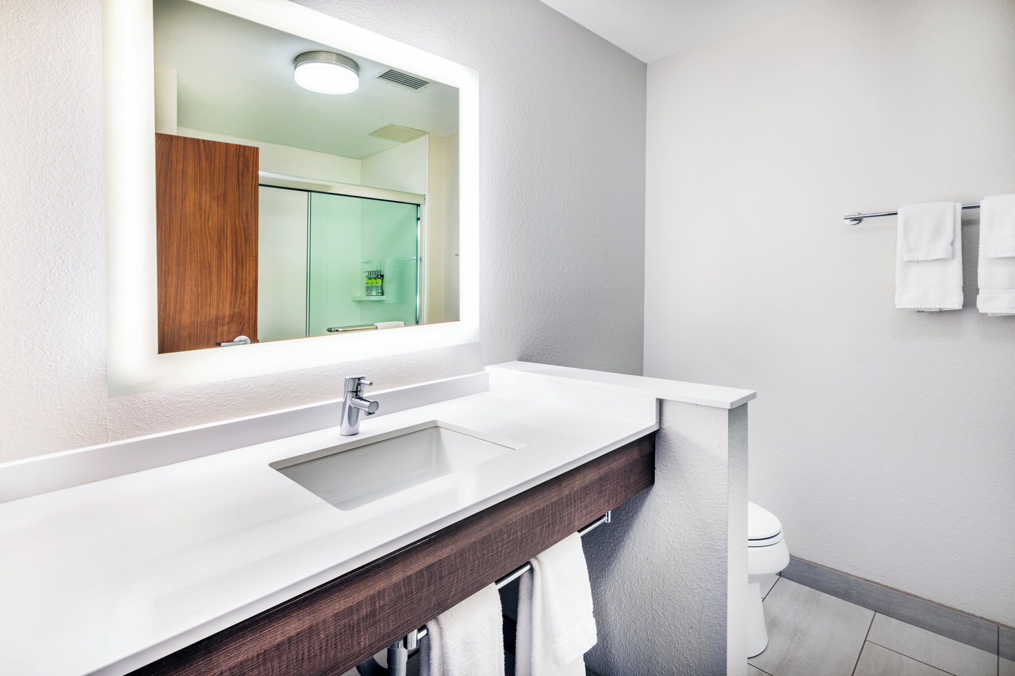 A modern bathroom with a white sink, a mirror, and a towel rack.