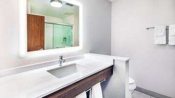 A modern bathroom with a white sink, a mirror, and a towel rack.