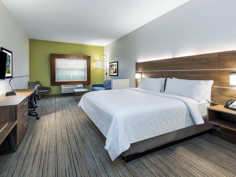 A hotel room with a bed, desk, chair, and a television.