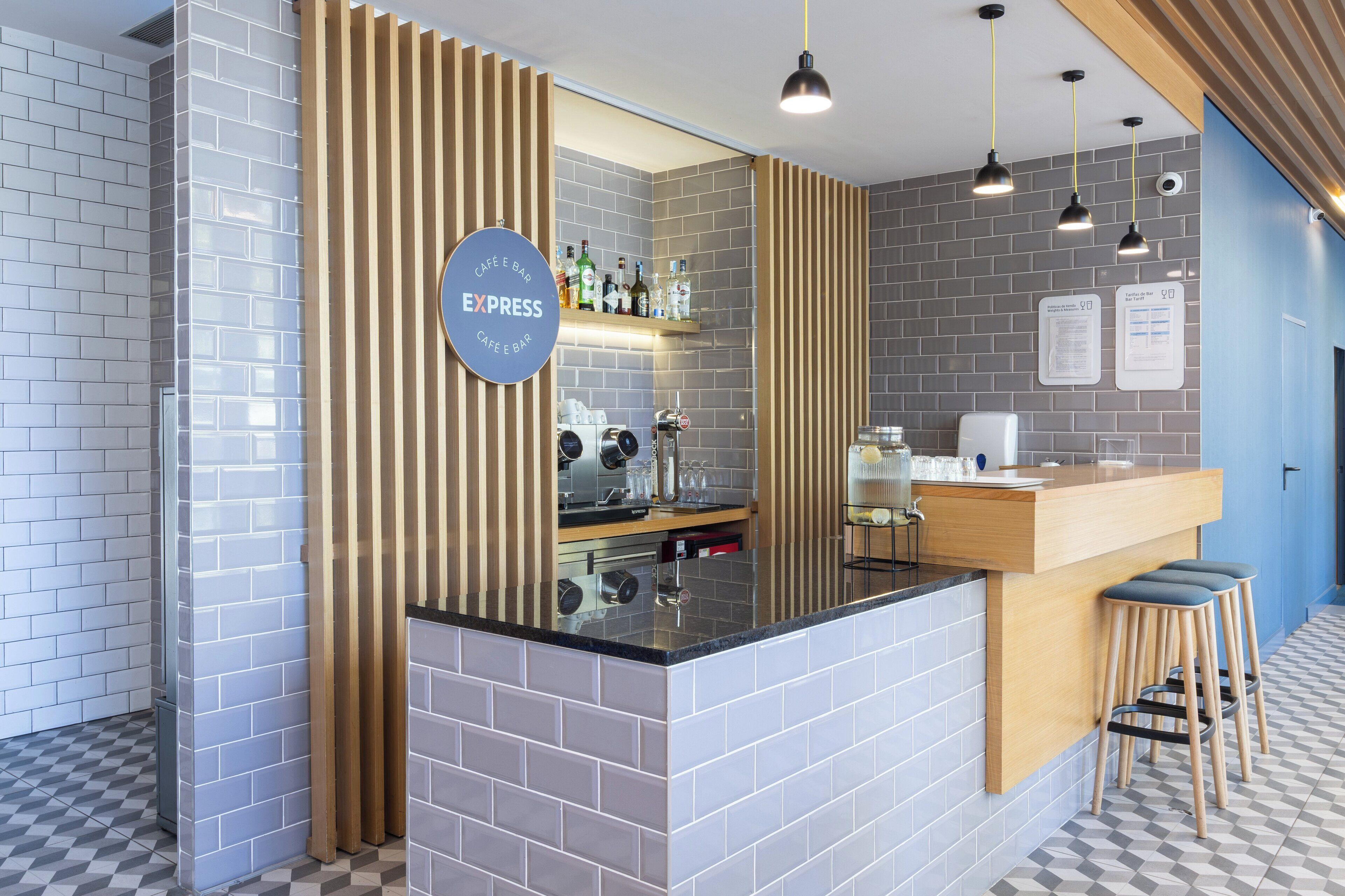 Zona de bar moderna con barra, taburetes y un letrero que indica que es un café y bar.