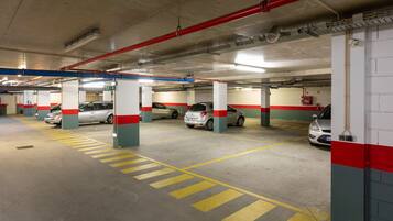 A multi-level parking garage with several cars parked, concrete pillars, and yellow parking lines.