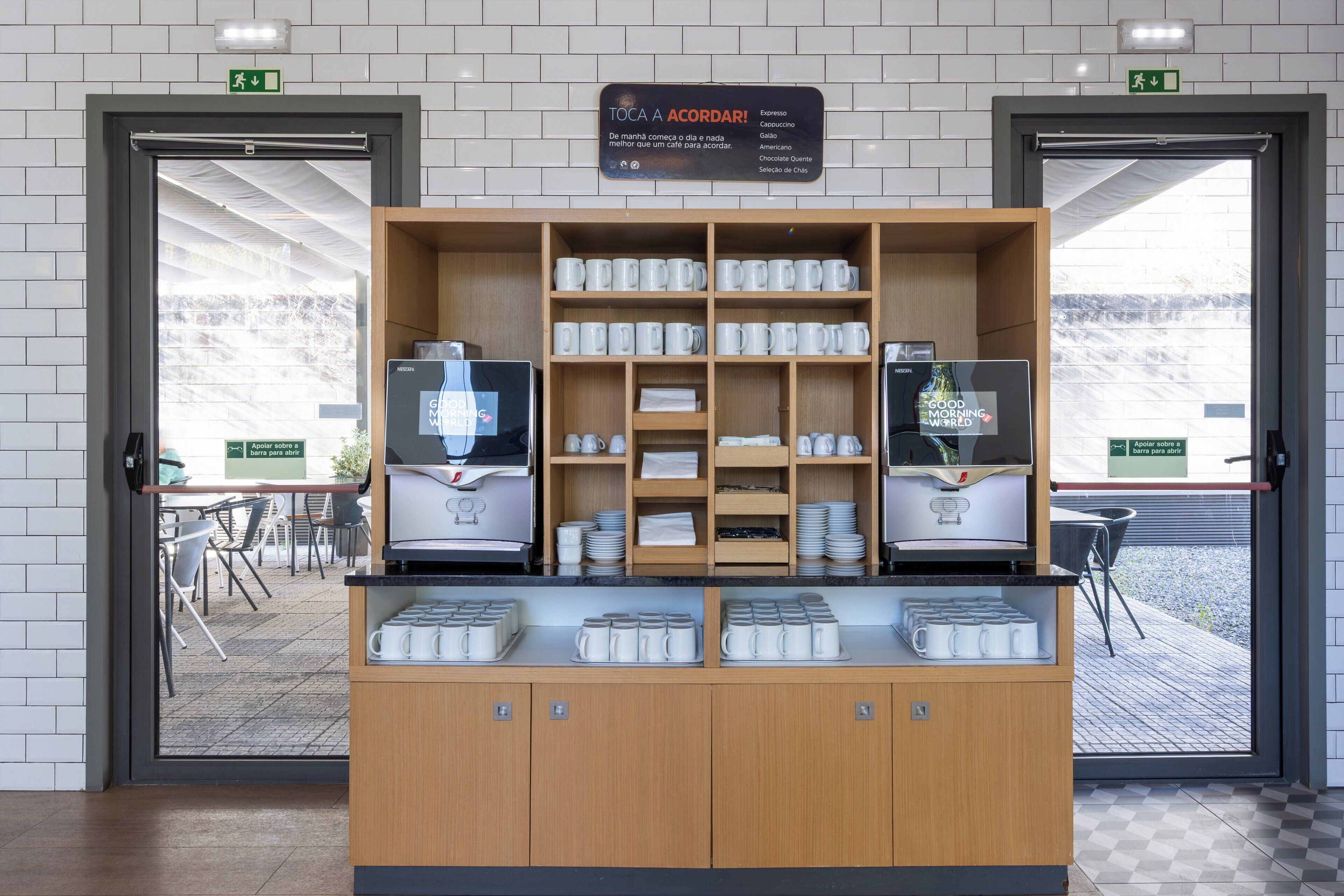 A coffee station with multiple coffee machines and a variety of coffee cups and saucers.