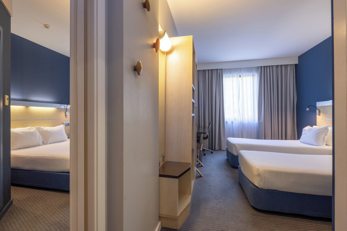 Ein Hotelzimmer mit zwei Betten, einem Schreibtisch und einem Stuhl.