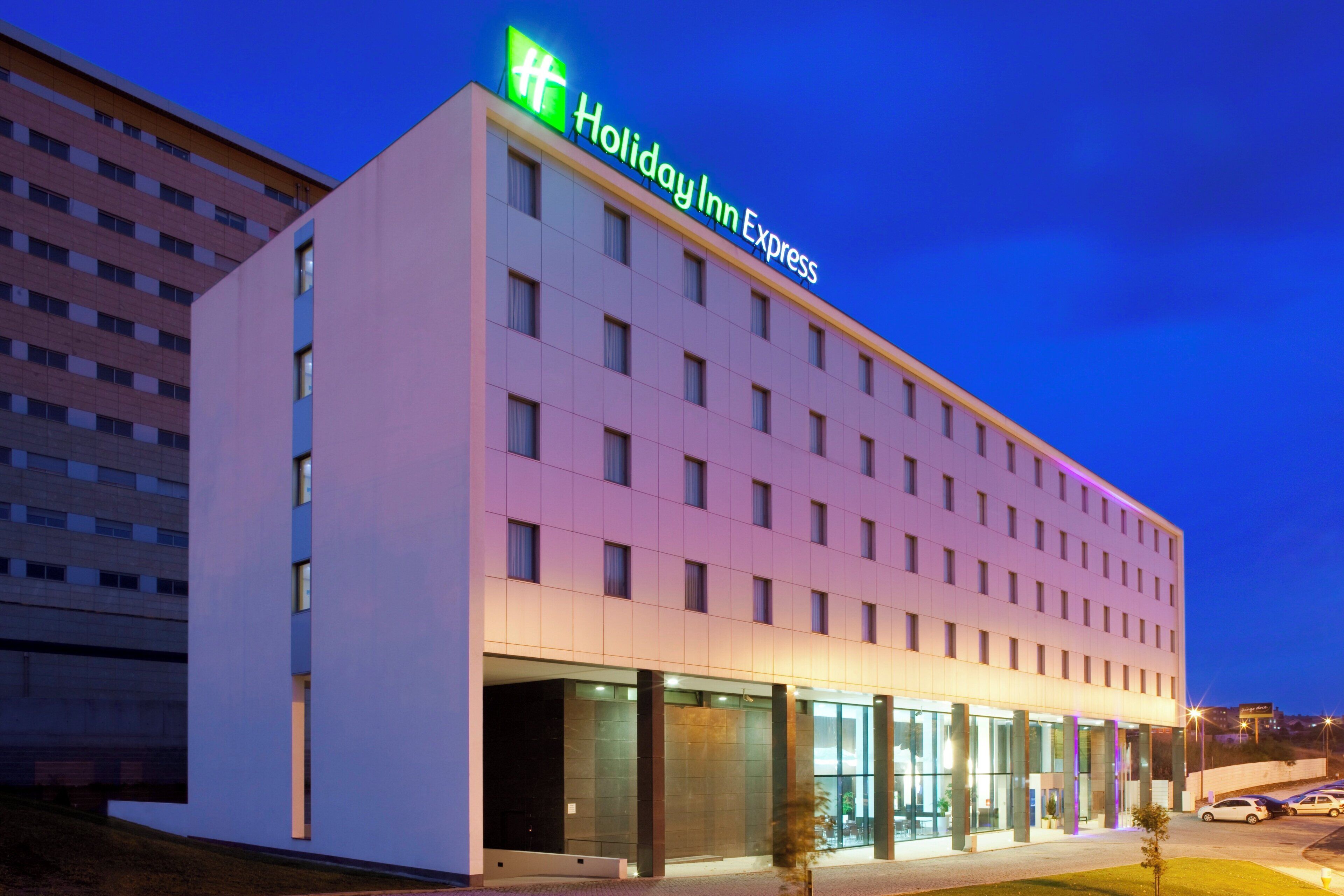 Un hotel Holiday Inn Express con una fachada moderna, ventanas amplias y un techo plano.