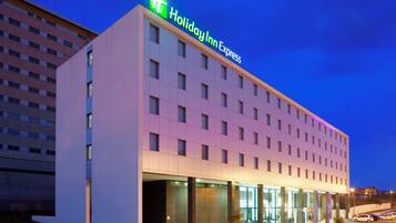 Un hotel Holiday Inn Express con una fachada moderna, ventanas amplias y un techo plano.