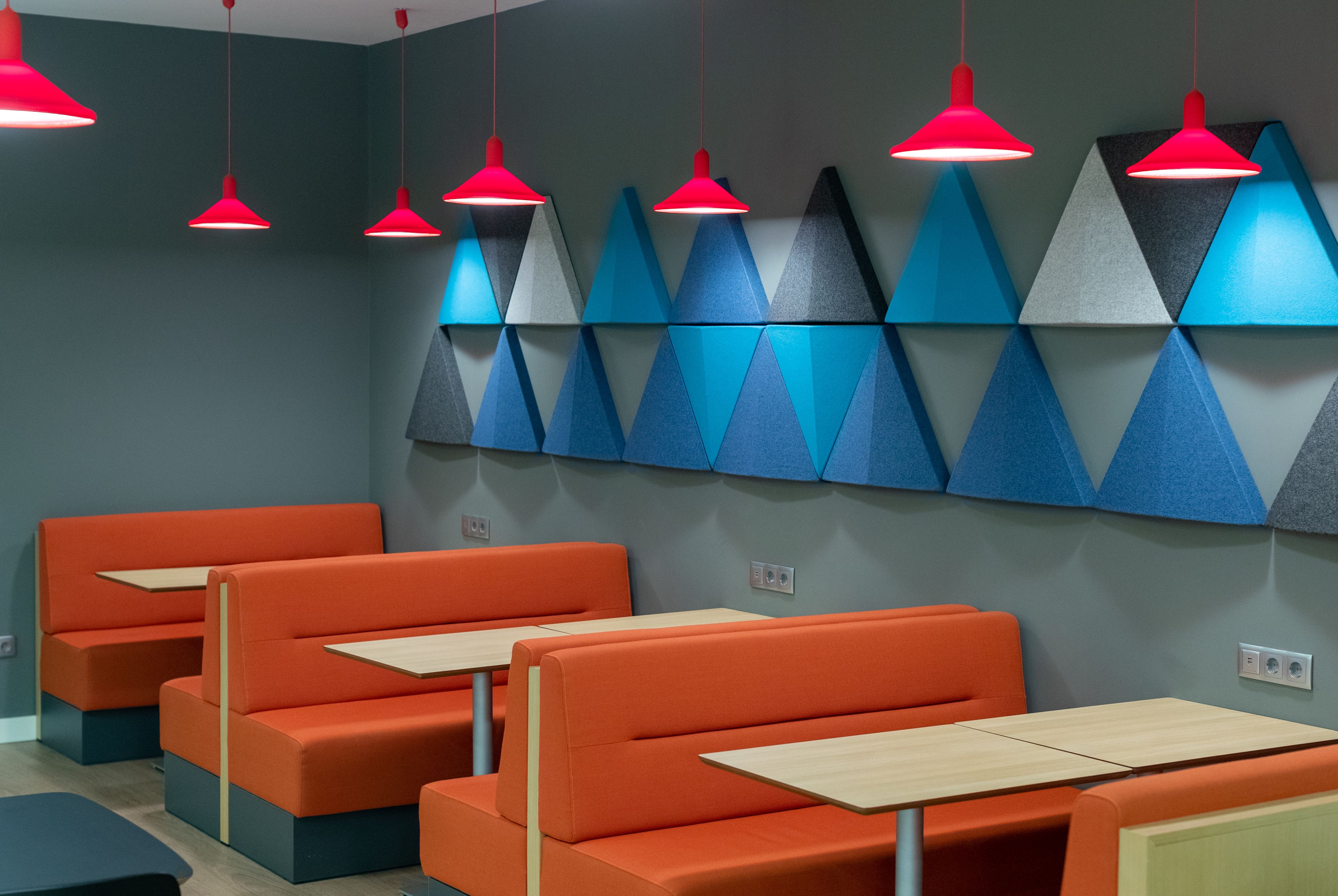 Een restaurant met oranje banken en rode hanglampen.