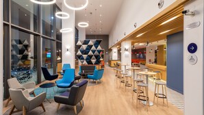 A modern interior with a bar area, seating with round tables, and a geometric wall design. - Holiday Inn Express Porto - Exponor by IHG (Matosinhos)
