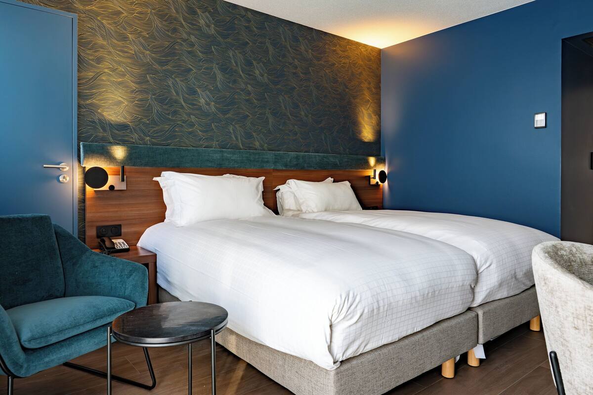 Ein Hotelzimmer mit einem großen Bett, einer blauen Akzentwand, einem Holz-Kopfteil und einem kleinen runden Tisch.