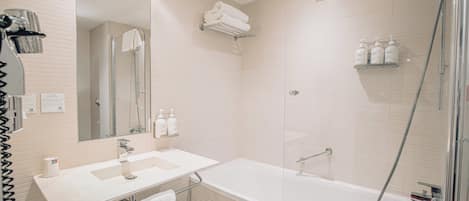 A modern bathroom with a glass-enclosed shower, a white sink with a mirror, and a bathtub.