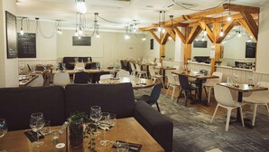 L’intérieur d’un restaurant, avec des poutres en bois, plusieurs tables et des chaises.