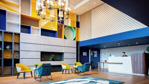 Un hall d’entrée moderne avec un comptoir d’accueil, un espace salon et un lustre.