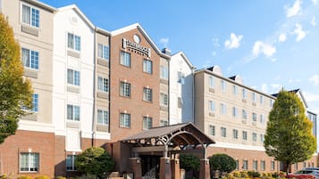A Staybridge hotel with a brick facade, multiple windows, and a covered entrance.