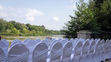 Rows of white chairs with a view of a river and trees in the background.