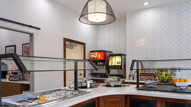 A breakfast bar with a variety of food options, a Coca-Cola dispenser, and a coffee machine.