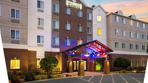 A Staybridge hotel with a modern facade, multiple windows, and a well-lit entrance. - Staybridge Suites Rochester University by IHG (Rochester)