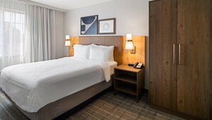 A hotel room with a large bed, two bedside tables with lamps, a wardrobe, and a window with curtains. - Staybridge Suites Rochester University by IHG (Rochester)