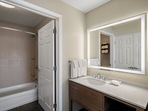 A bathroom with a bathtub, a sink, a mirror, and a towel rack.