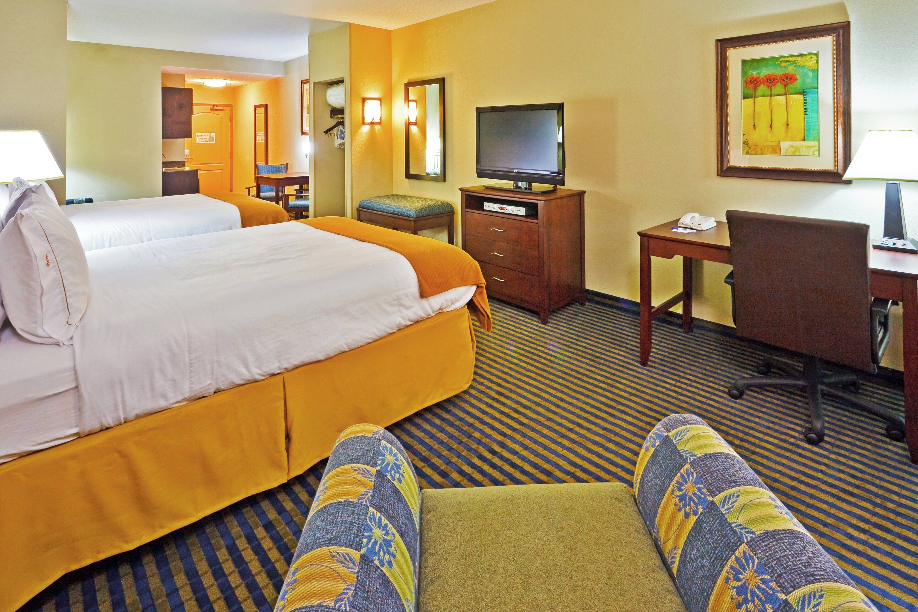A hotel room with two beds, a television, a desk with a phone, and a chair.