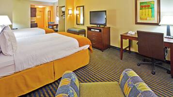 A hotel room with two beds, a television, a desk with a phone, and a chair.