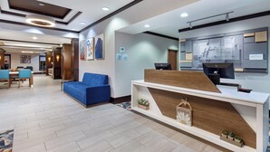 A hotel lobby with a reception desk, seating area, and a dining setup. - Holiday Inn Express Hotel Ooltewah Springs-Chattanooga by IHG (Ooltewah)