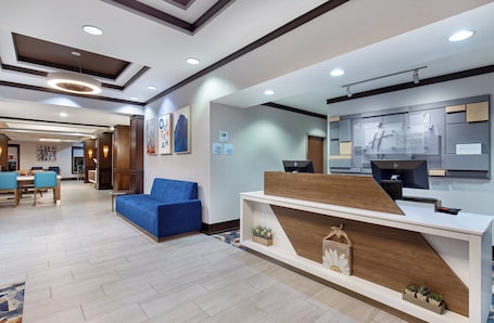A hotel lobby with a reception desk, seating area, and a dining setup.