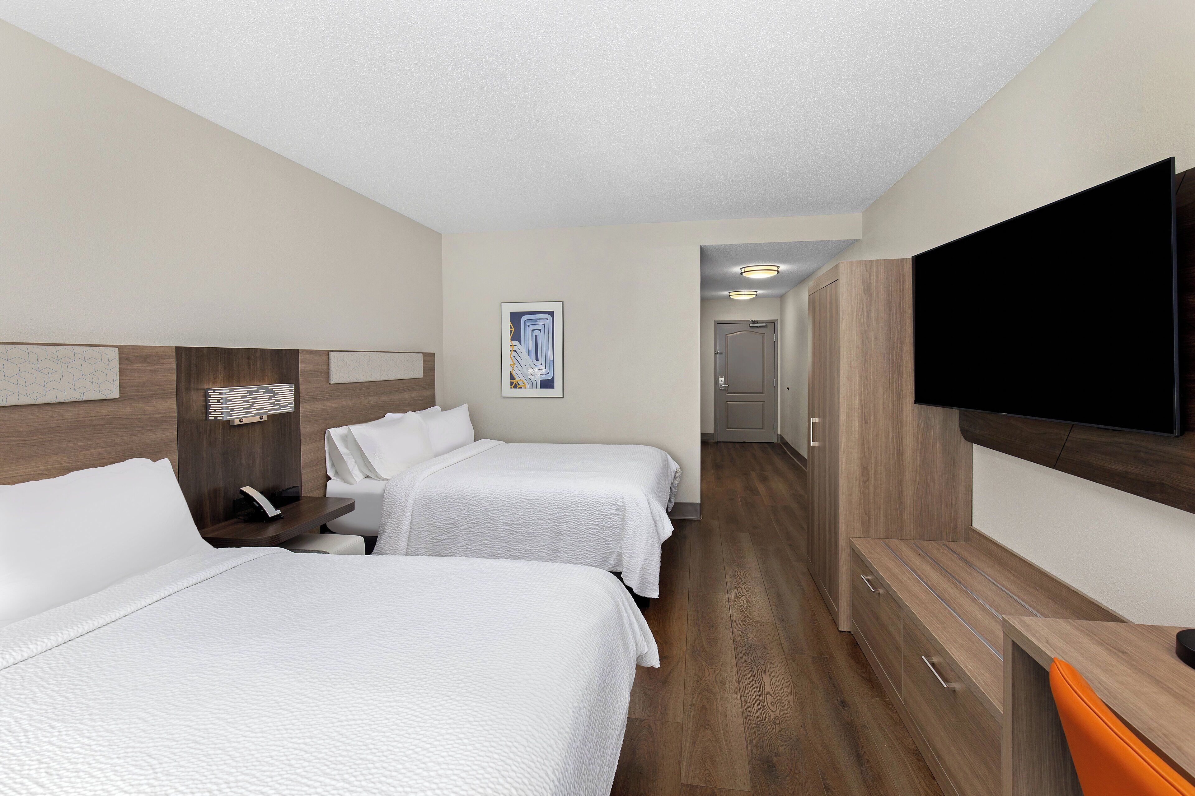 A hotel room with two beds, a TV, a desk, and a wardrobe.