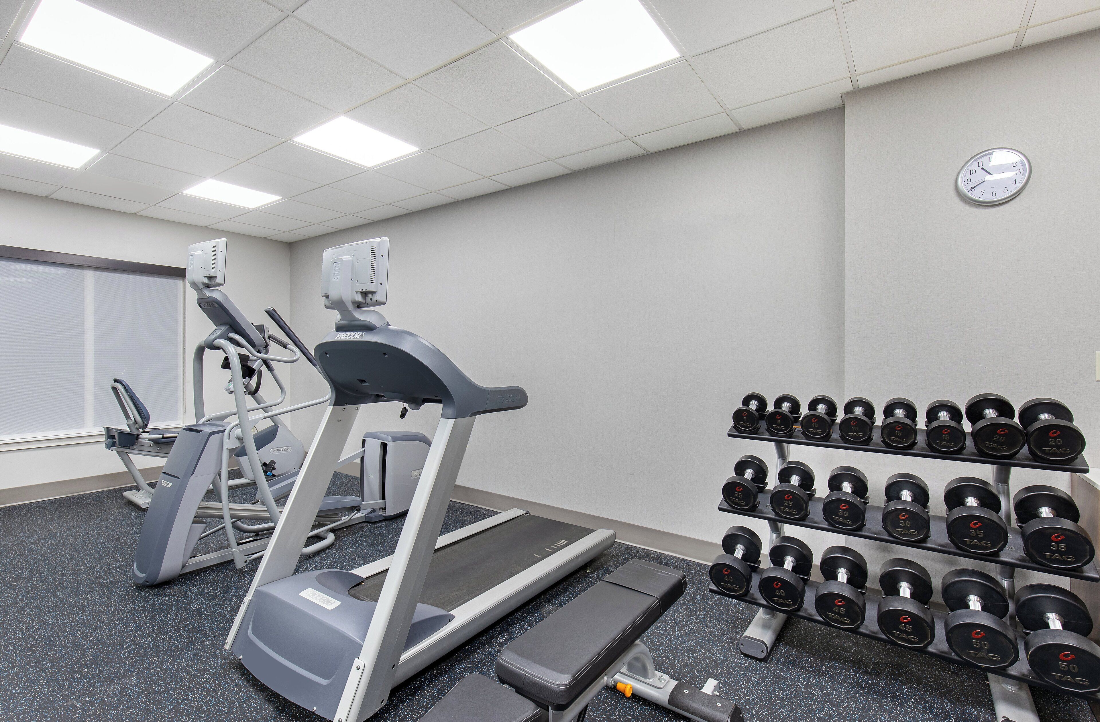 A gym with treadmills, a stair climber, and a rack of dumbbells.